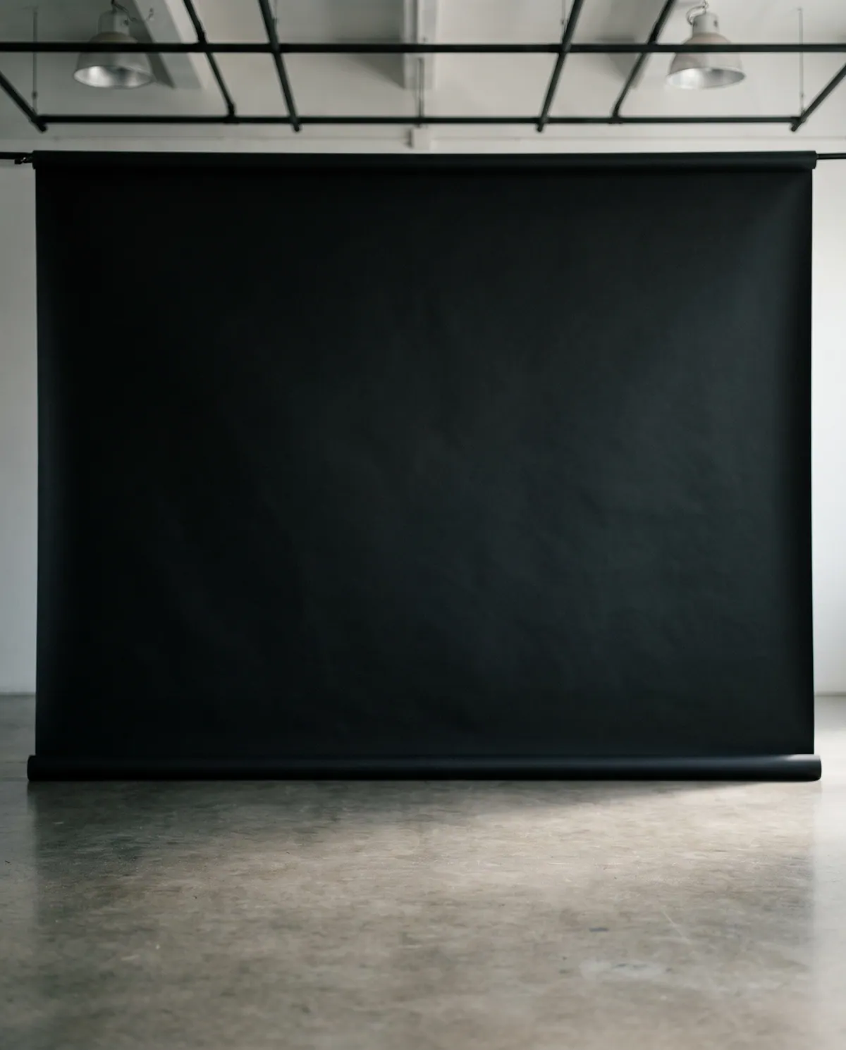 A photographer's studio with a black seamless backdrop, awaiting a portrait session.